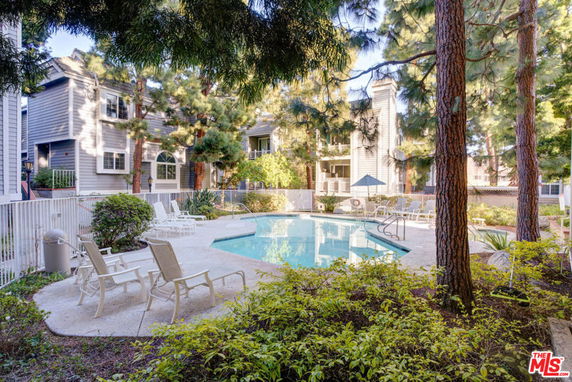Outdoor swimming pool area with lounge chairs and surrounding greenery.
