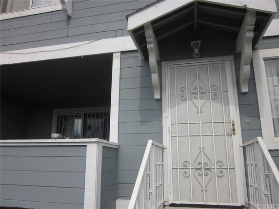 Front view of a building entrance with stairs and a decorative metal door.