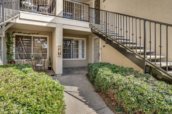 Front view of a ground floor apartment with stairs and plants.