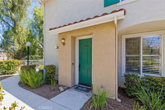 Front view of a house with a green front door and a window with shutters.