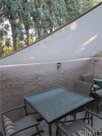Outdoor patio with a glass table, chairs, and a sunshade.