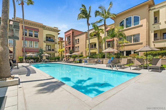 Outdoor swimming pool area surrounded by multi-story buildings with balconies.