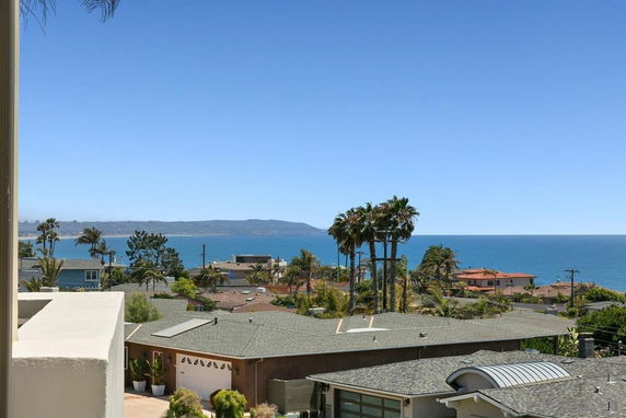 View of houses overlooking the ocean with a clear blue sky.