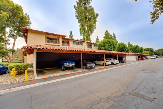 Outdoor covered parking area in front of a two-story building.