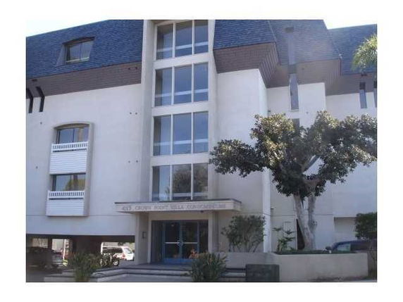 Front view of a multi-story residential building with large windows and a prominent entrance.