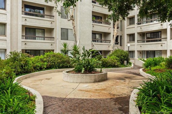 Outdoor view of apartment building with multiple balconies and landscaped walkway.