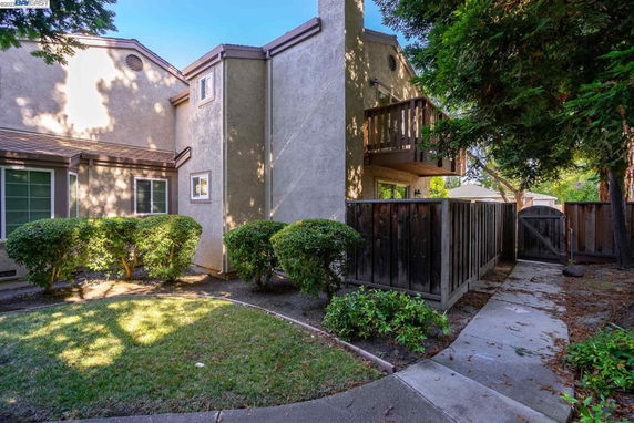 Front view of a townhouse with a small private balcony and fenced yard.