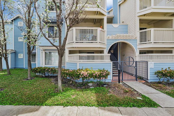 Front view of a multi-story residential building with balconies and gated entrance.