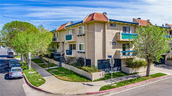 Front view of a multi-story building with balconies and tiled roof.
