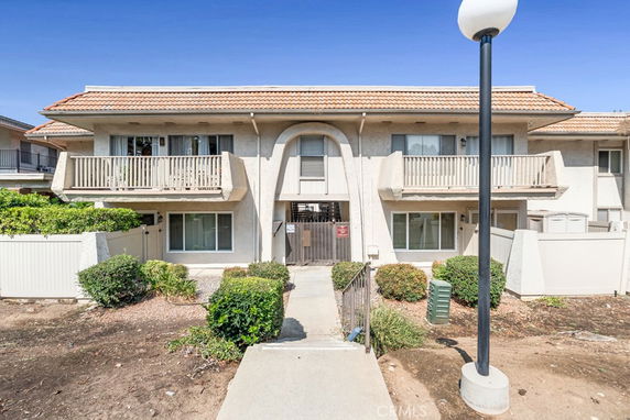 Front view of a two-story residential building with balconies and a central entrance.