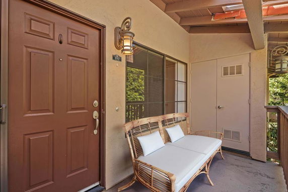 Entrance view of a house with a wooden door, bench, and exterior lighting.