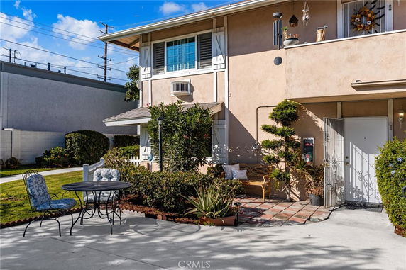 Front view of a two-story house with a small garden and outdoor seating area.