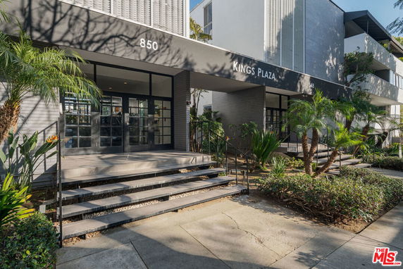 Front view of a modern multi-story building named Kings Plaza with glass doors and stairs leading to the entrance.