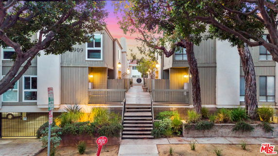 Front view of a multi-level residential building with stairs leading to the entrance.