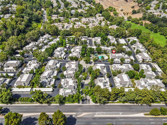 Aerial view of a residential area with multiple houses, streets, and greenery.