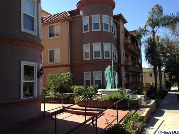 Front view of a multi-story building with bay windows and a statue in front.
