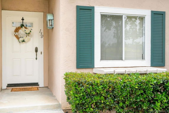 Front view of a house entrance with a white door and window with green shutters.