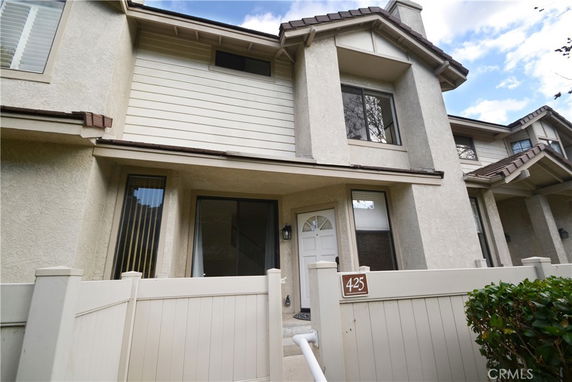 Front view of a two-story house with an entrance gate and number plaque.
