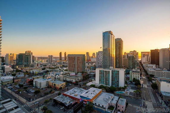 Wide angle view of a city skyline with tall buildings at sunset.