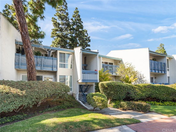 Front view of a two-story residential building with multiple balconies and external stairs.