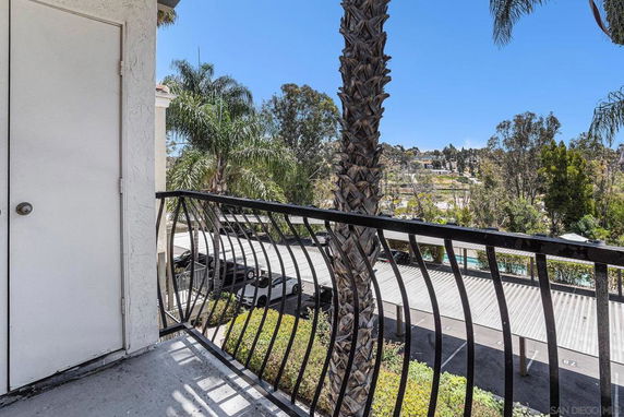 Balcony view overlooking parking area and lush greenery.