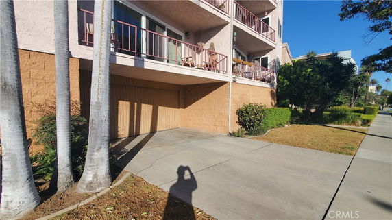 Front view of a multi-story building with balconies and a closed garage area at the bottom.