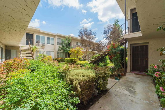 View of an apartment complex with staircases and greenery in a courtyard.
