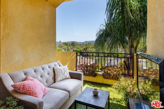 Outdoor balcony with sofa and table overlooking a scenic view.