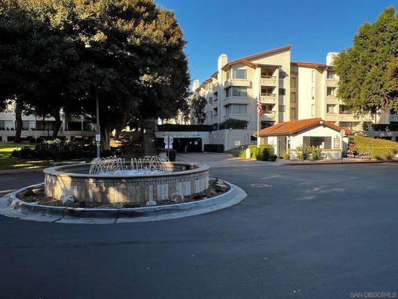 Front view of a multi-story residential building with a fountain in front.
