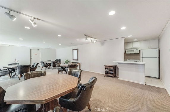 Interior view of a club house with tables, chairs, and a small kitchenette.
