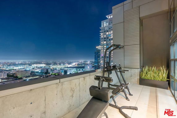 Rooftop area with gym equipment overlooking cityscape at night.