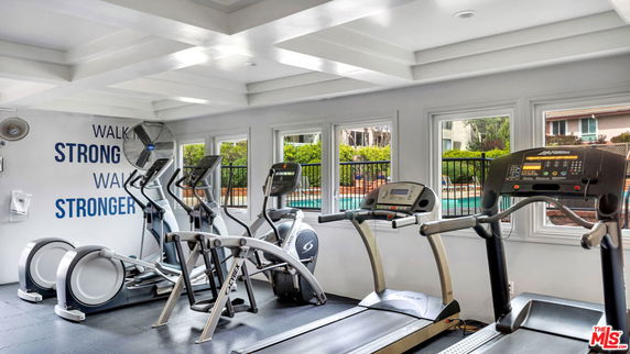 Indoor gym area with exercise machines and motivational wall text.