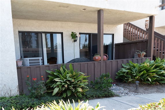 Front view of a residential building with a patio and potted plants.