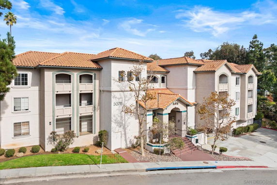 Front view of a multi-story apartment building with a tiled roof and arched windows.