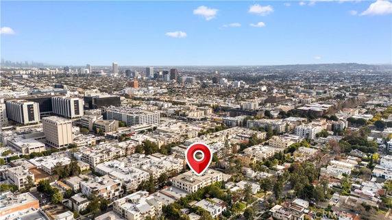 Aerial view of a city with multiple buildings and a marker indicating a specific location.