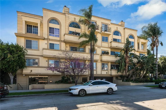 Front view of a multi-story residential building with balconies and arched windows.