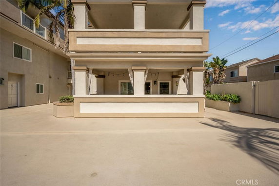 Front view of a multi-story house with balcony and large driveway