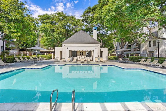 Outdoor swimming pool area with lounging chairs and a view of a building.