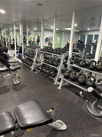 Indoor gym area with exercise equipment and weights.