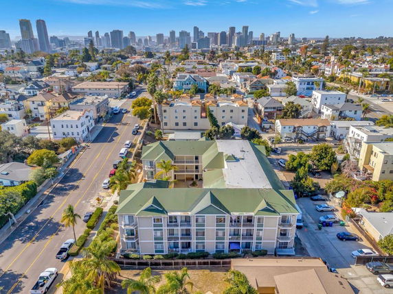 Aerial view of a residential area with mid-rise buildings and a city skyline in the background.