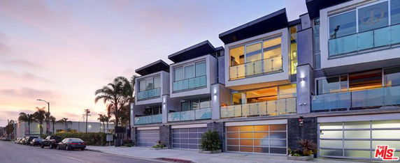 Front view of modern multi-story residential building with large glass windows and balconies.