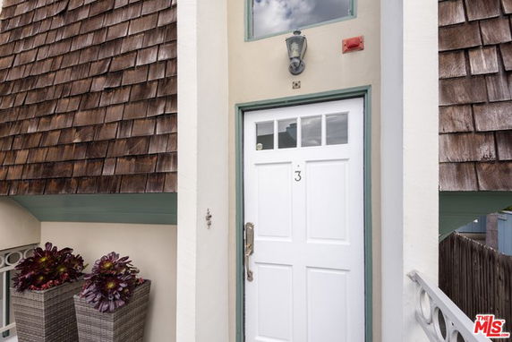 Front view of a building entrance with shingled roofing and a decorative white door.