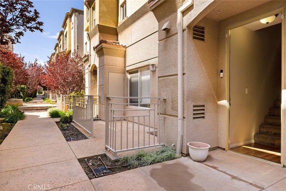 Front view of a multi-story building with a walkway and small fenced entrance area.