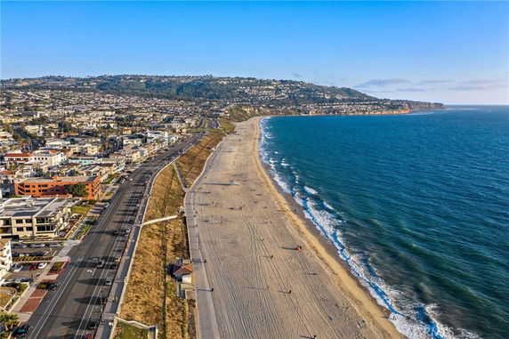 Panoramic view of a coastline with sandy beach and ocean, alongside a developed urban area.