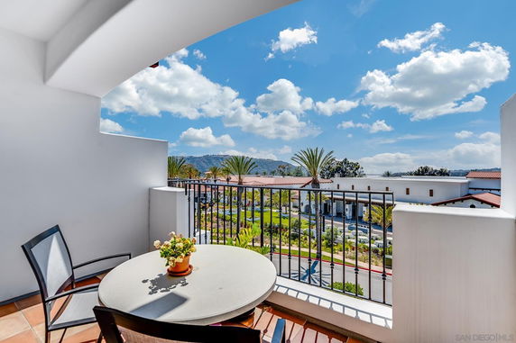 Balcony view overlooking a scenic area with buildings and palm trees.
