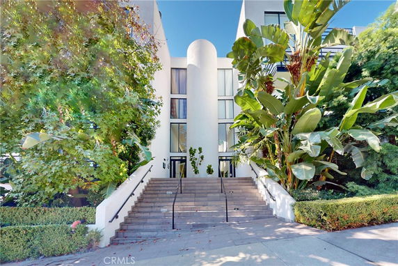 Front view of a building with a central entrance and surrounding greenery.