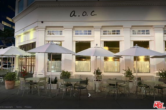 Front view of a building with outdoor seating and umbrellas.