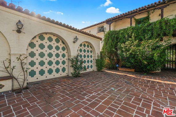 Front view of a house with arched design elements and vine-covered walls.