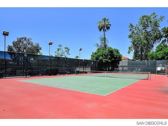 Tennis court with surrounding high fence and trees
