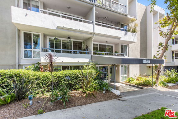Front view of a multi-story apartment building with balconies and an entrance canopy.